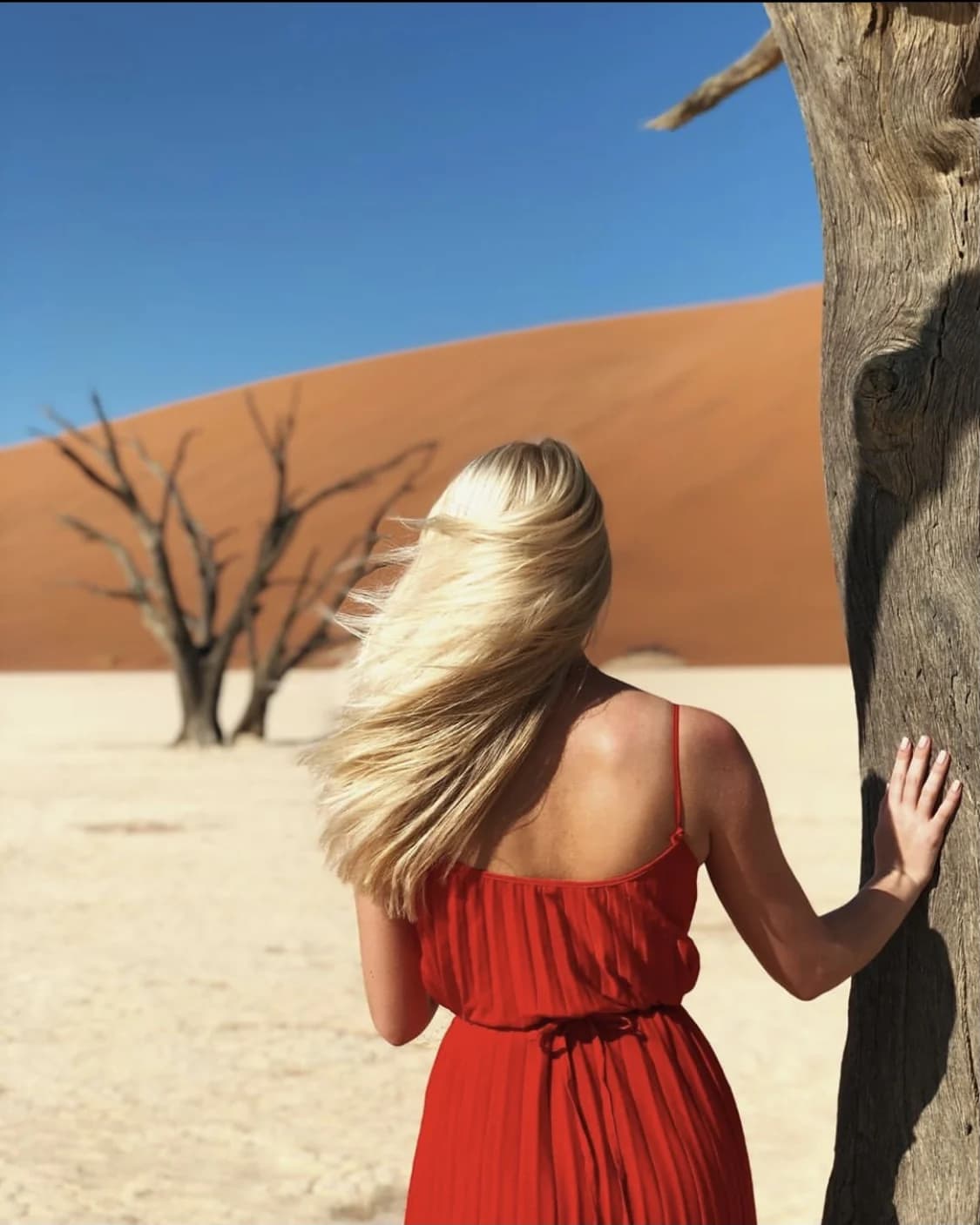 A student in a red dress exploring the dunes and trees of Deadvlei